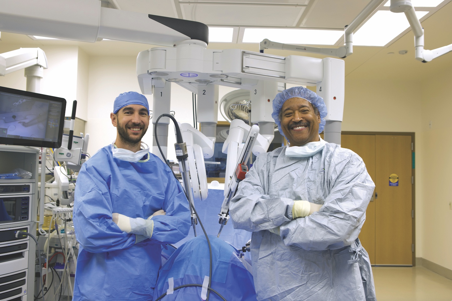 Drs. Jason Collins and John Robertson III pose in front of the da Vinci surgical system